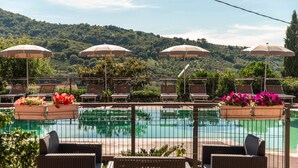 A poolside area with lounge chairs and umbrellas, surrounded by a fence, overlooking a pool and a hilly landscape. - Bb La Mortella With Pool (Roccadaspide)