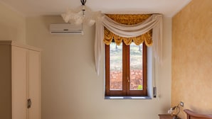 A bedroom with a bed, a nightstand, a wardrobe, a window with curtains, and an air conditioning unit. - Bb La Mortella With Pool (Roccadaspide)