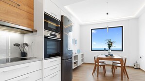 Une cuisine moderne avec des meubles blancs, un réfrigérateur noir et un coin repas comprenant une table et des chaises en bois.