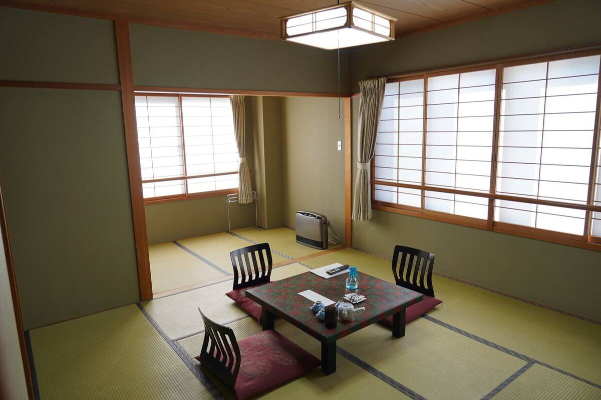 A traditional Japanese room with tatami flooring, a low table with cushions, and sliding doors.