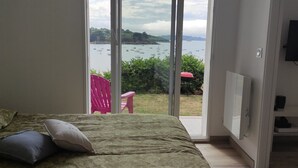 Un dormitorio con cama, televisión y vista a barcos en el agua a través de una puerta corrediza.