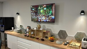 Una cocina moderna con encimera de madera, un televisor montado en la pared y diversos alimentos y electrodomésticos.