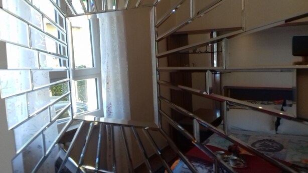 Ein Zimmer mit einem großen Fenster, Metallregalen und einem roten Teppich.