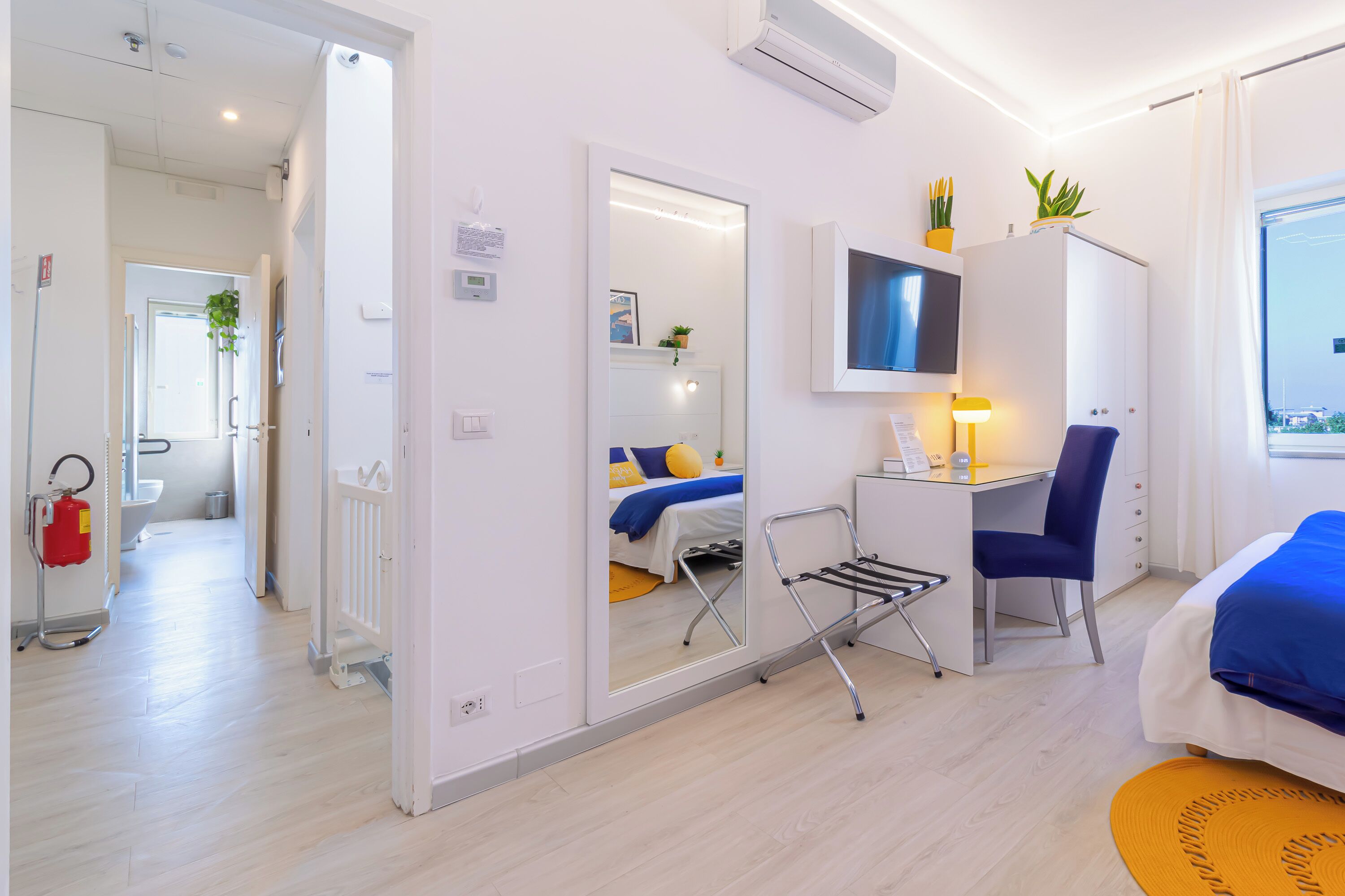 Una habitación de hotel moderna con cama, escritorio, silla y televisión montada en la pared.
