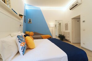 A bedroom with a bed, pillows, a blue wall, a radiator, and a door. - La Terrazza Family Holidays Your Dream Getaway in Sorrento Coast (Sant'Agnello)