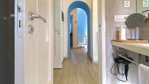A hallway with a wooden floor, a door with a handle, a blue archway, and a mirror on a counter. - La Terrazza Family Holidays Your Dream Getaway in Sorrento Coast (Sant'Agnello)