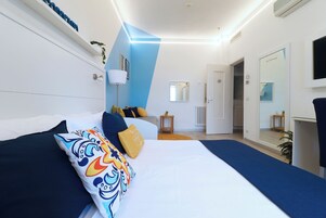 A modern hotel room with a large bed, a bedside table, a mirror, and a TV.