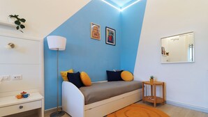 A modern bedroom with a bed, bedside table, lamp, and a small side table with a plant. - La Terrazza Family Holidays Your Dream Getaway in Sorrento Coast (Sant'Agnello)