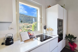 A modern kitchen with a window, a kettle, a microwave, and a potted plant. - La Terrazza Family Holidays Your Dream Getaway in Sorrento Coast (Sant'Agnello)