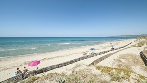 A beach with a clear sky, a sandy shore, and a wooden fence running parallel to the water. - Beautiful apartment in Baja Sardinia (Baja Sardinia)