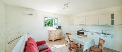 Een moderne keuken met witte kasten, een eettafel en rieten stoelen.