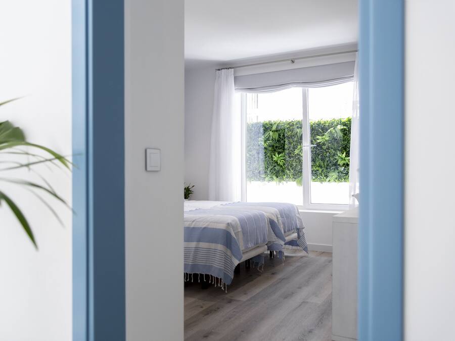 A bedroom with a bed, a window, and a plant.
