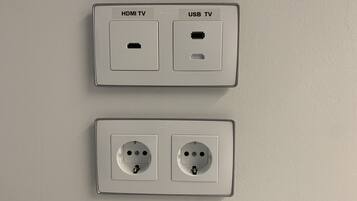 Dos tomas de corriente en la pared, una con puertos HDMI y USB para televisión, y la otra con dos tomas de corriente estándar.