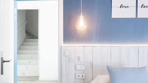 Une pièce avec un escalier, un luminaire fixé au mur et un lit avec un oreiller.