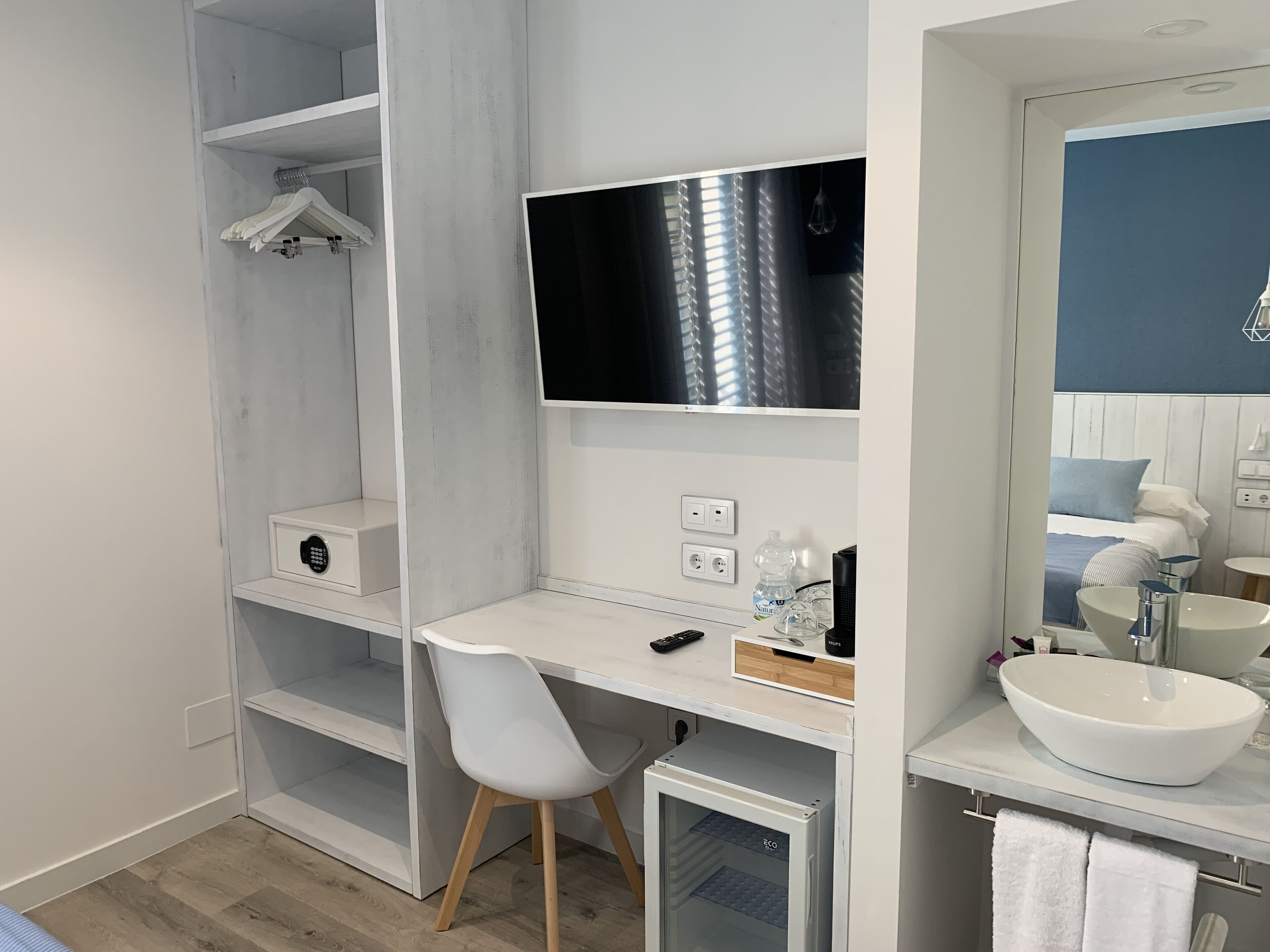 Un baño moderno con tocador blanco, un espejo grande, lavabo integrado y zona de ducha.