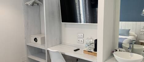 Un baño moderno con tocador blanco, un espejo grande, lavabo integrado y zona de ducha.