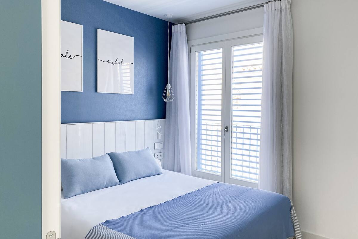 Un dormitorio con una cama, un espejo en la pared y una ventana con cortinas.