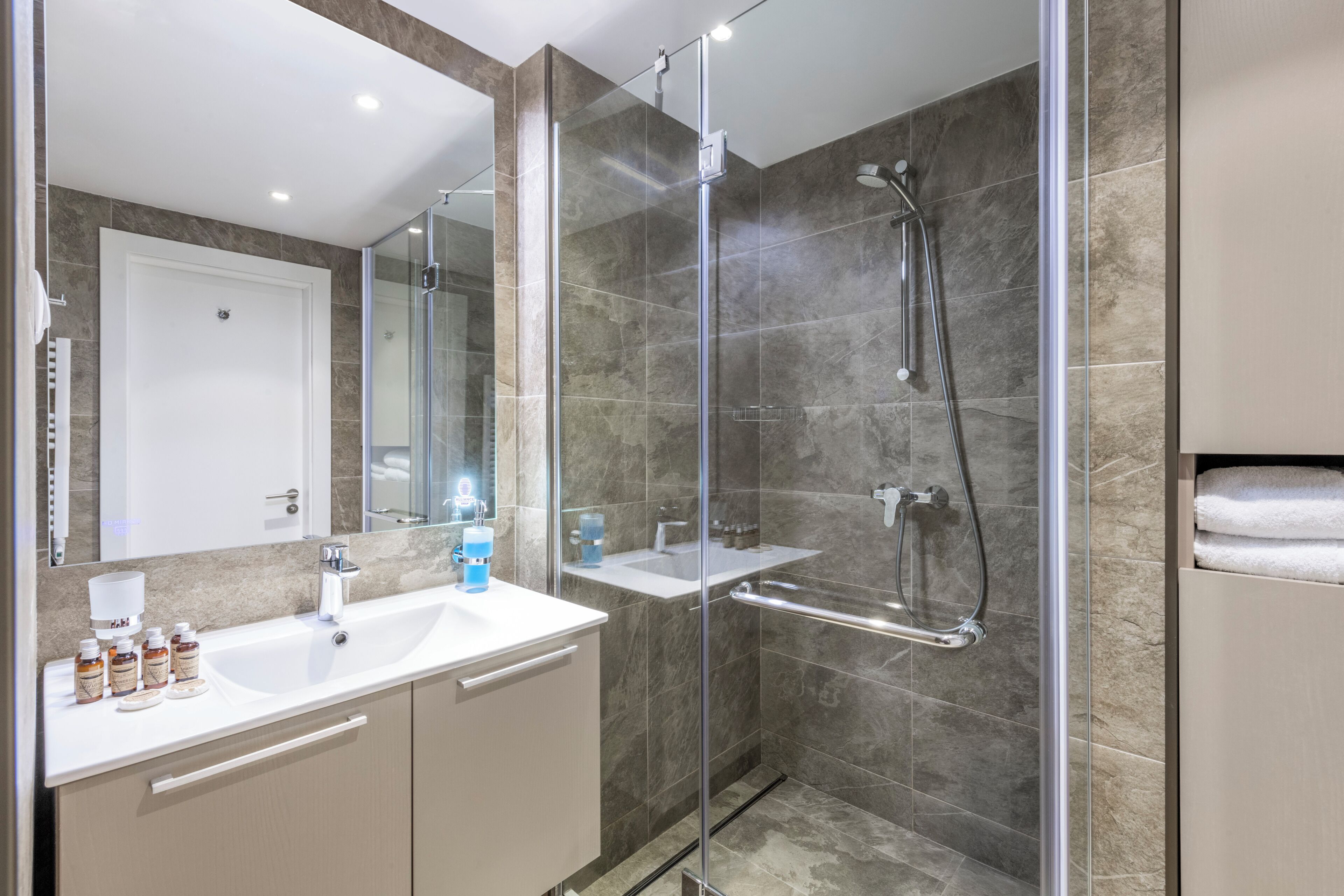 Een moderne badkamer met een douchecabine van glas, een wit wastafelmeubel en een spiegel.