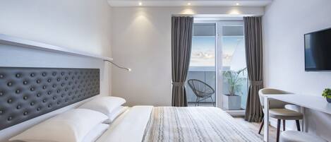 A modern hotel room with a large bed, a desk, and a TV.