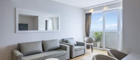 A modern living room with a grey sofa, a round coffee table, and a dining area with a white table and chairs.