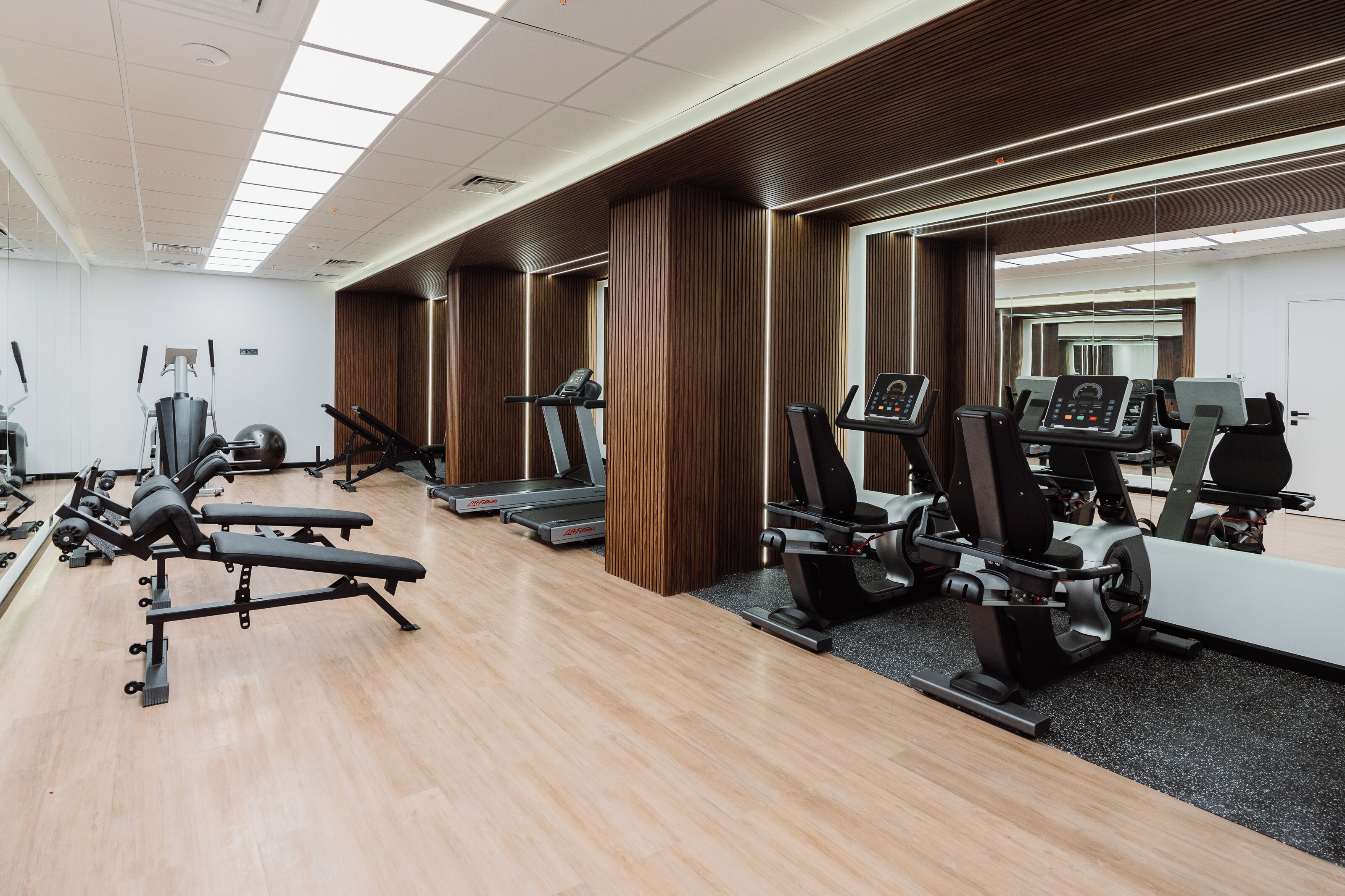 A gym with exercise equipment, wooden paneling, and a large mirror.