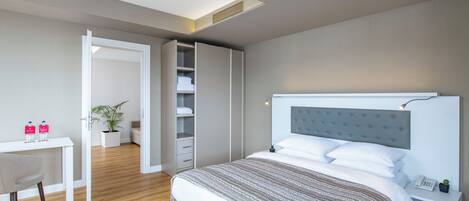 A modern bedroom with a bed, bedside tables, a desk, and a wardrobe.