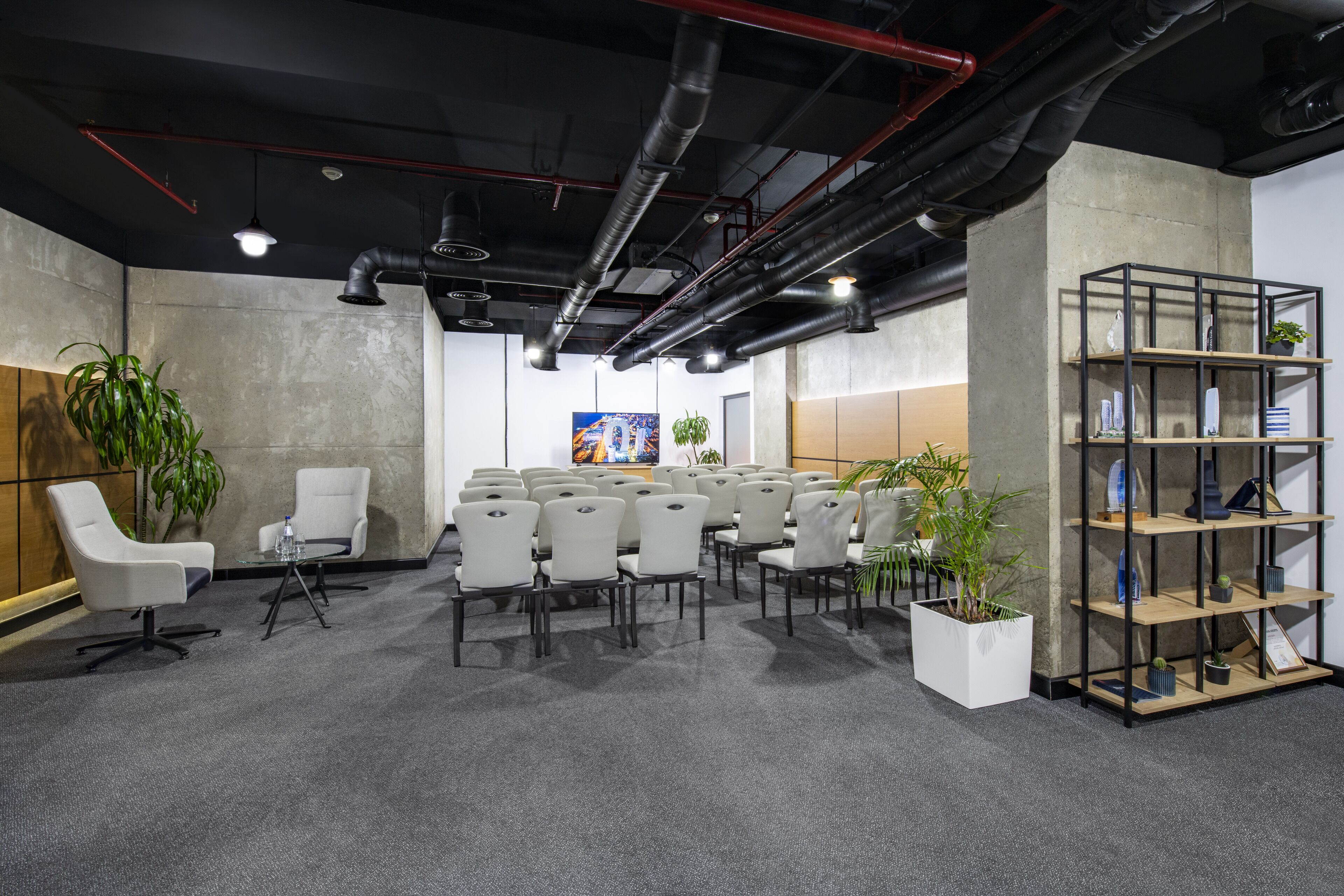 A conference room with rows of chairs, a whiteboard, and a plant.