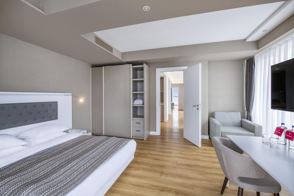 A modern hotel room with a bed, a desk, and a TV.