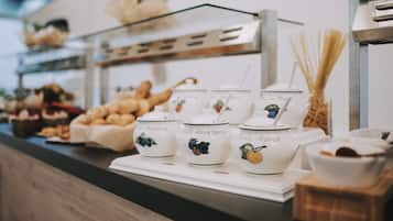 Zona de bufé con diversas opciones de comida y teteras identificadas con distintos sabores a fruta.