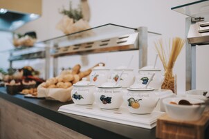 A buffet area with various food items and tea pots labeled with different fruit flavors.