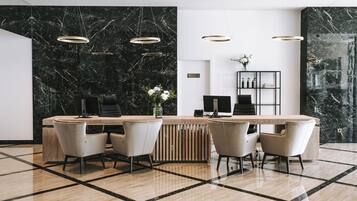 A modern reception area with a marble wall, a reception desk, and a seating area with chairs.