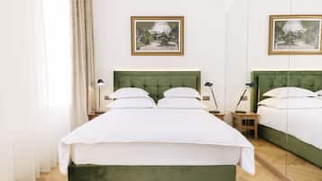 A neatly arranged bedroom with a green upholstered bed, white bedding, two bedside tables with lamps, and framed pictures on the wall.