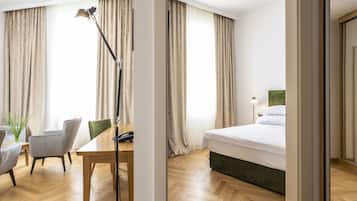 Ein Hotelzimmer mit Holzboden, einem Bett mit grünem Kopfteil, einem Schreibtisch mit Telefon und einem Stuhl.