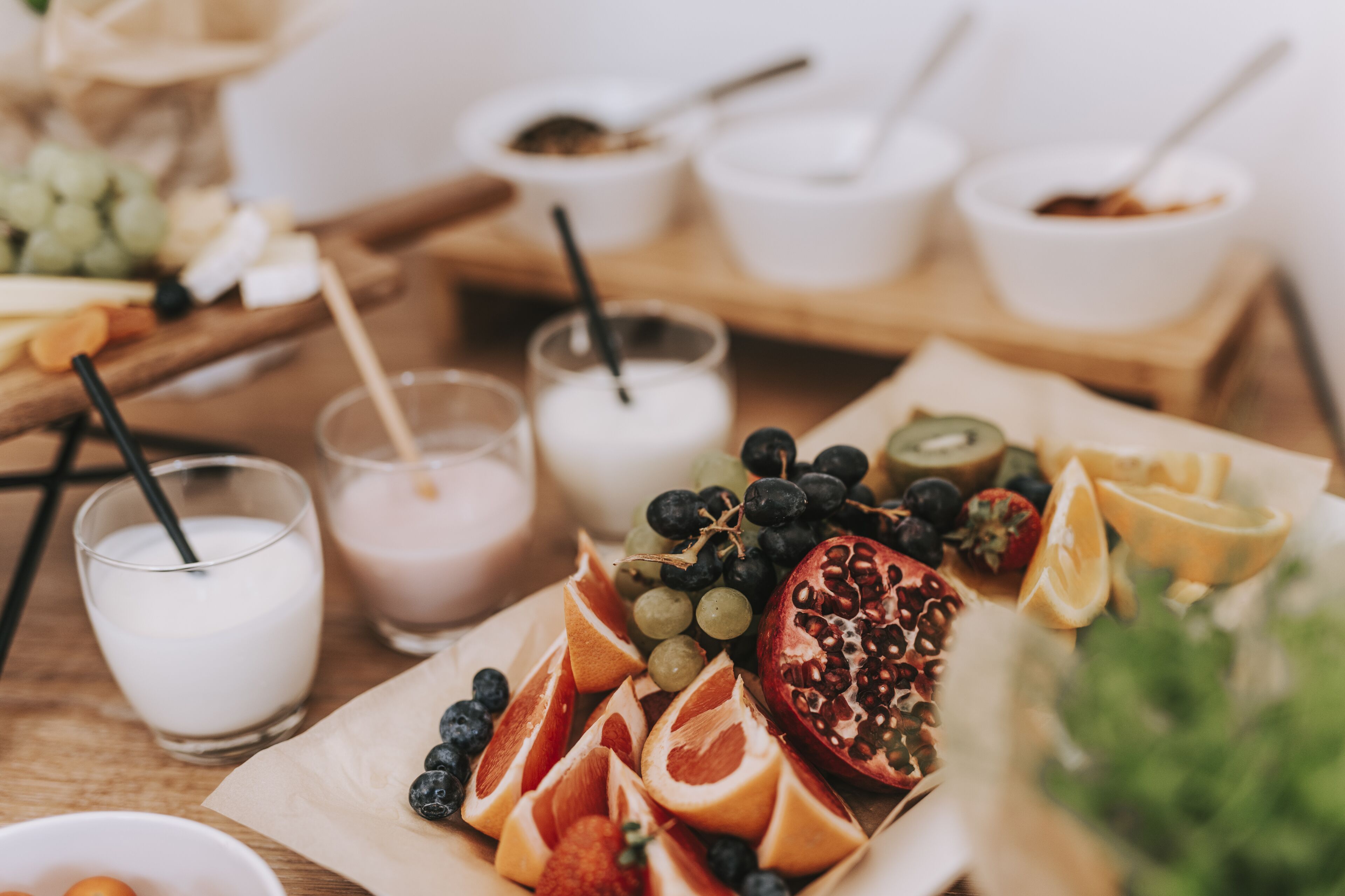 A table with various fruits, a bowl of yogurt, and a glass of milk.