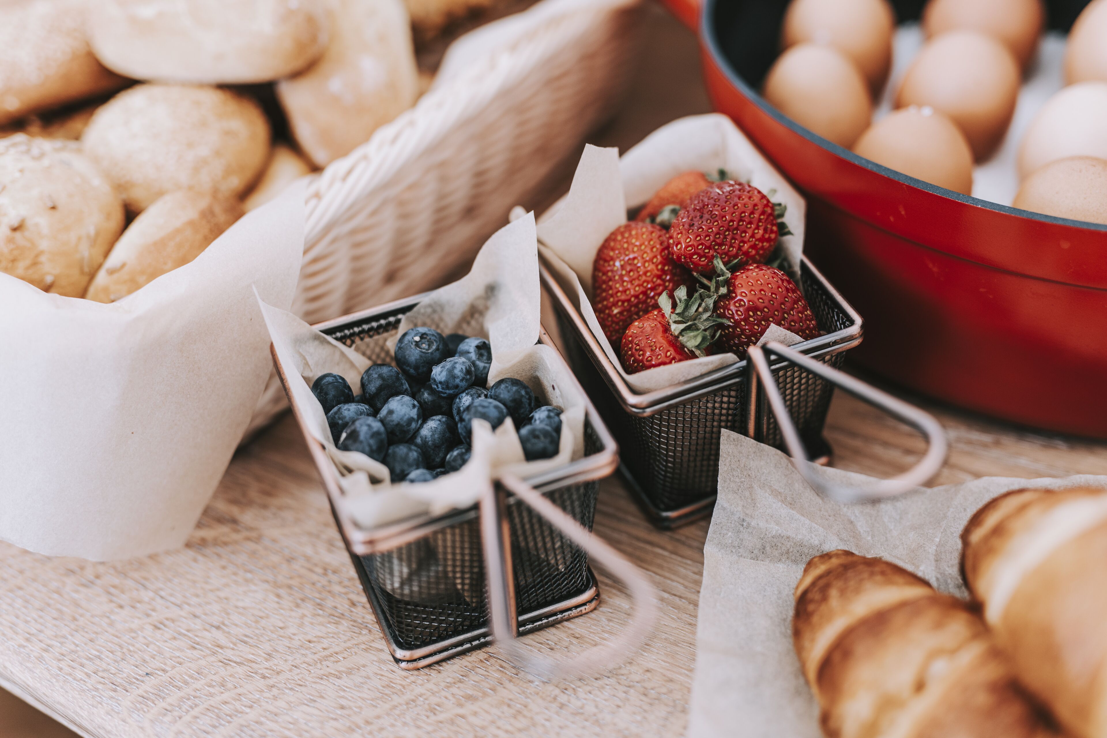Un bufé de desayuno con cestas de arándanos, fresas y huevos.