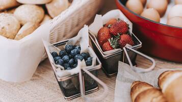 Un bufé de desayuno con cestas de arándanos, fresas y huevos.