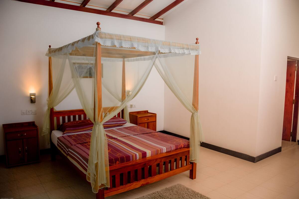 Una cama con dosel, una mesita de noche y una lámpara de pared.