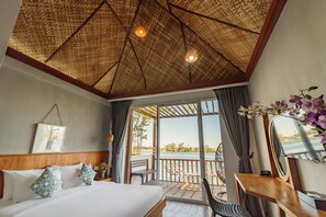 A bedroom with a large bed, a wooden headboard, a ceiling with a woven pattern, a balcony with a view of the water, and a desk with a mirror. - Phka Kravan Boutique (Kampot)