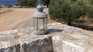 A stone wall with a lantern and a chessboard on a marble table. - Leonidas Stone Houses Near Beach 50 Meters Away From Tavern With Local Food (West Mani)