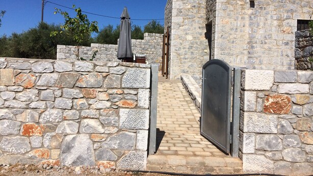 A stone-walled building with a paved entrance and a metal gate. - Leonidas Stone Houses Near Beach 50 Meters Away From Tavern With Local Food (West Mani)