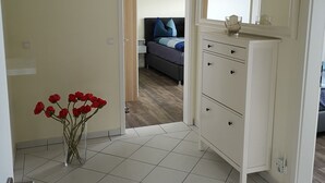 A modern bedroom with a bed, a dresser, and a bathroom visible through an open door.