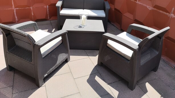 An outdoor patio area with wicker furniture, including two chairs and a table with a candle.