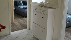 A room with a white dresser, a mirror, and a bed with blue bedding.
