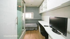 Un dormitorio pequeño y moderno con cama, televisor y ventana.