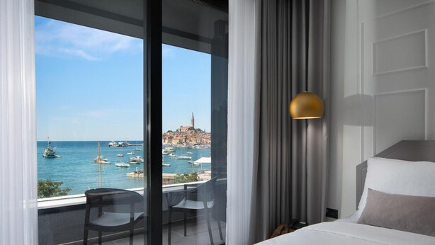 Habitación de hotel con un ventanal que ofrece vistas a un puerto deportivo y barcos.