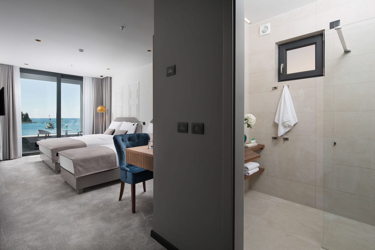 Ein modernes Hotelzimmer mit einem großen Bett, einem Schreibtisch und Blick aufs Meer.