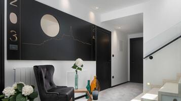A modern hallway with a black wall, a round mirror, and a staircase.