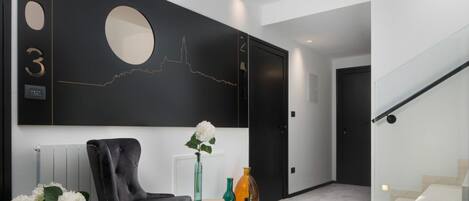 Un pasillo moderno con una pared negra, un espejo redondo y una escalera.