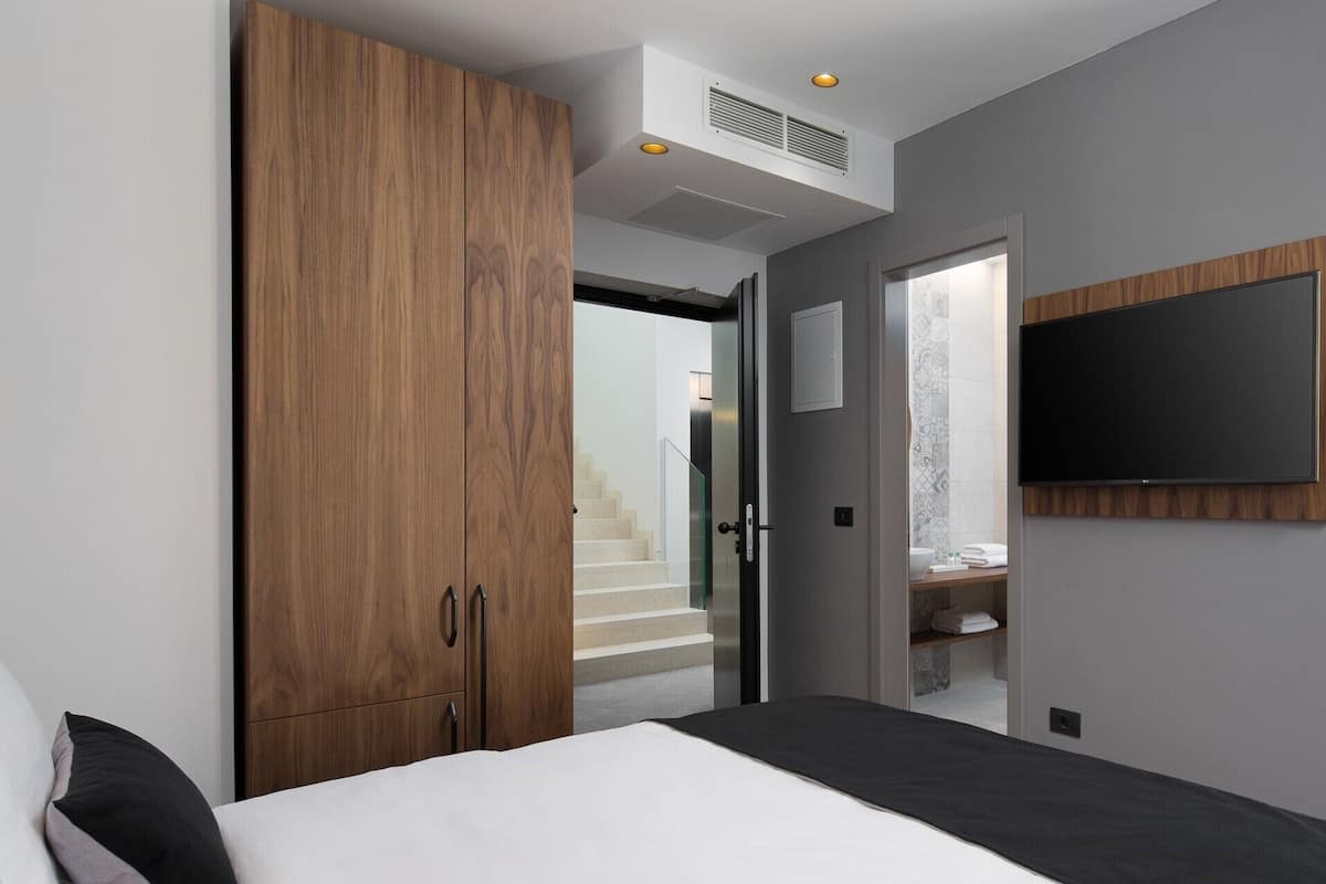 Ein modernes Schlafzimmer mit einem großen Bett, einem Holzschrank und einem an der Wand befestigten Fernseher.
