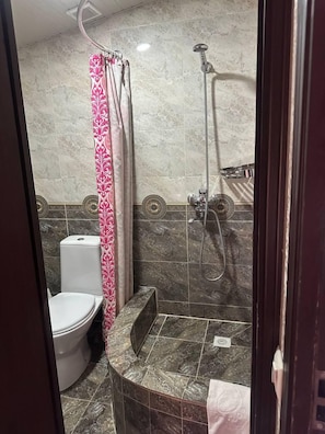 A bathroom with a toilet, shower, and marble tiles. - Sapphire Hotel (Tashkent)